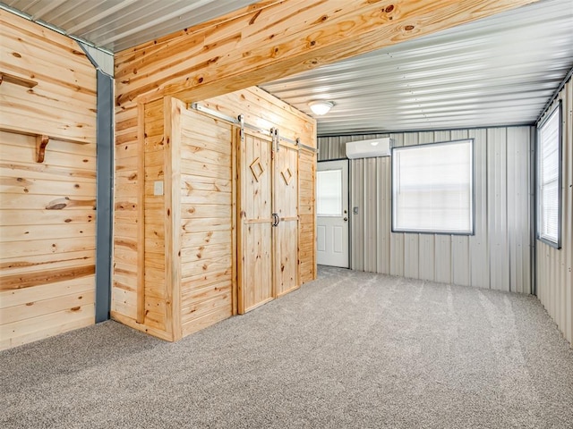 interior space with a wall unit AC, a barn door, and wood walls