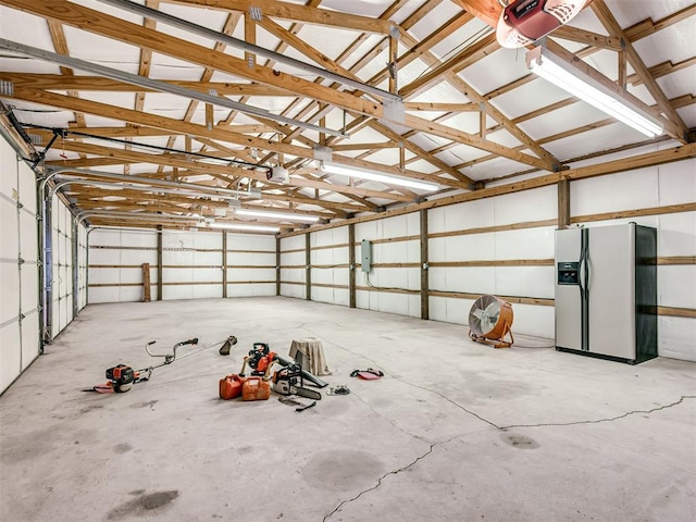 garage with a garage door opener and stainless steel refrigerator with ice dispenser