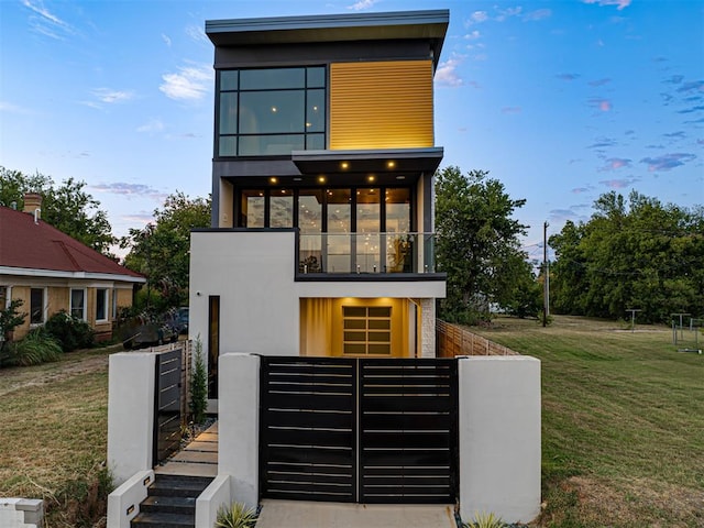 contemporary house featuring a balcony and a front lawn