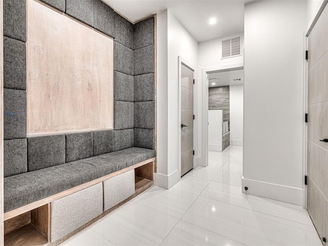 hallway featuring light tile patterned floors and tile walls