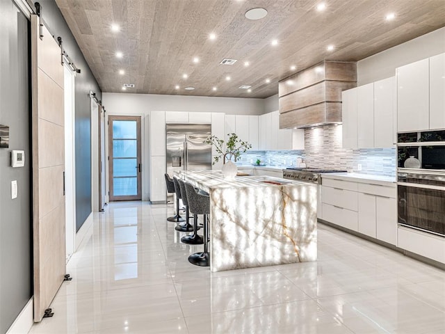 kitchen featuring a barn door, a spacious island, and white cabinetry