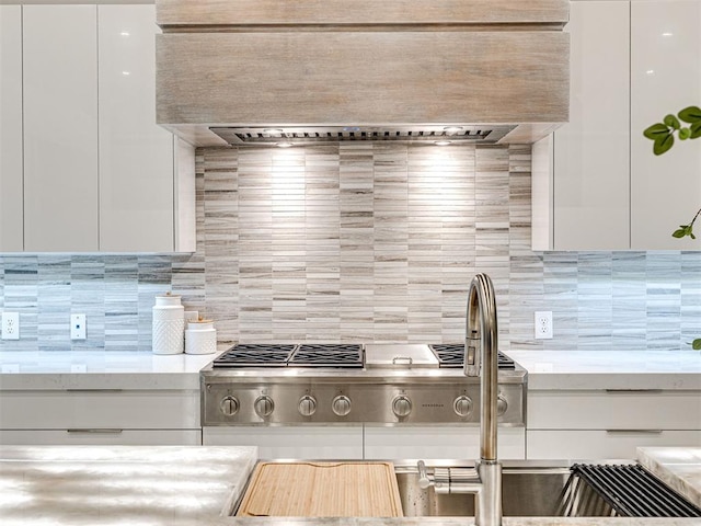 kitchen featuring tasteful backsplash, white cabinetry, wall chimney range hood, and stainless steel gas cooktop