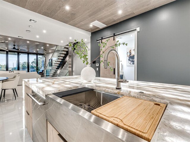 kitchen with a barn door, light brown cabinets, and wooden ceiling