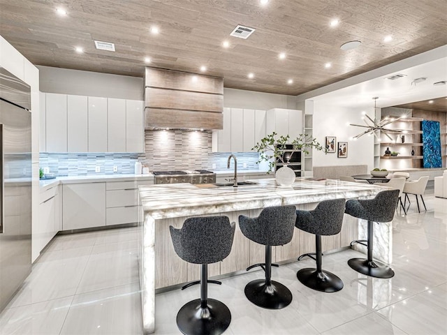 kitchen featuring premium range hood, white cabinets, a spacious island, and a kitchen breakfast bar