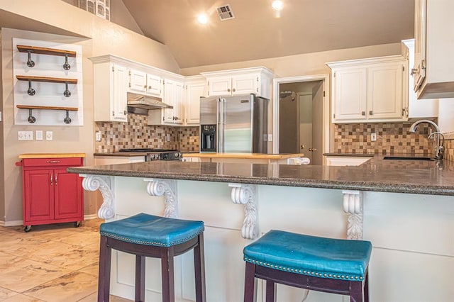 kitchen featuring a kitchen bar, sink, high quality fridge, and lofted ceiling