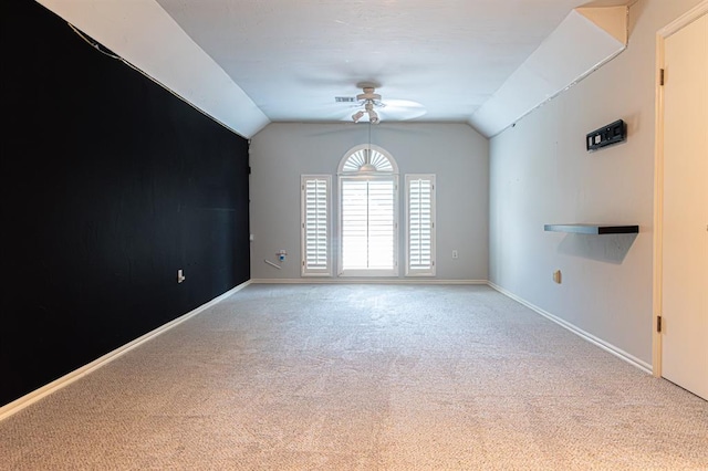 empty room with ceiling fan, light colored carpet, and vaulted ceiling