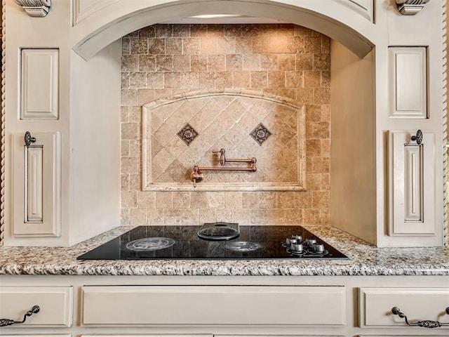 kitchen with decorative backsplash, light stone countertops, and black electric cooktop