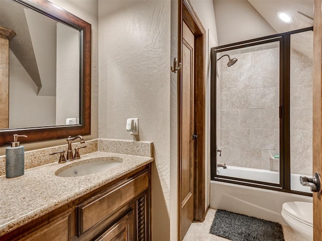 full bathroom featuring combined bath / shower with glass door, vanity, tile patterned floors, and toilet