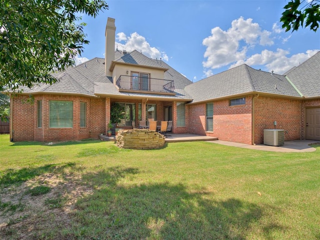 rear view of property featuring a balcony, a yard, a patio, and central AC