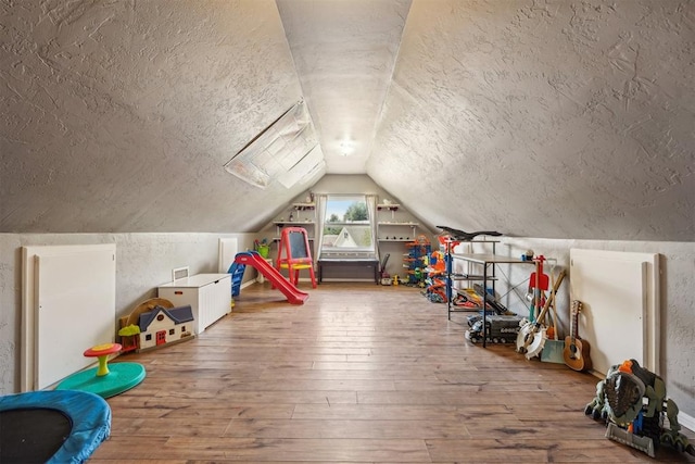 recreation room with wood-type flooring, a textured ceiling, and lofted ceiling