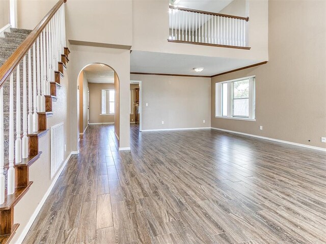 interior space featuring wood-type flooring, a high ceiling, and ornamental molding