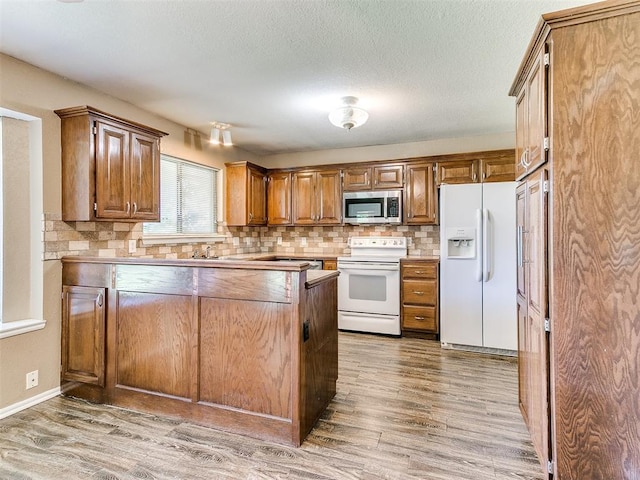 kitchen featuring tasteful backsplash, hardwood / wood-style floors, a textured ceiling, and white appliances