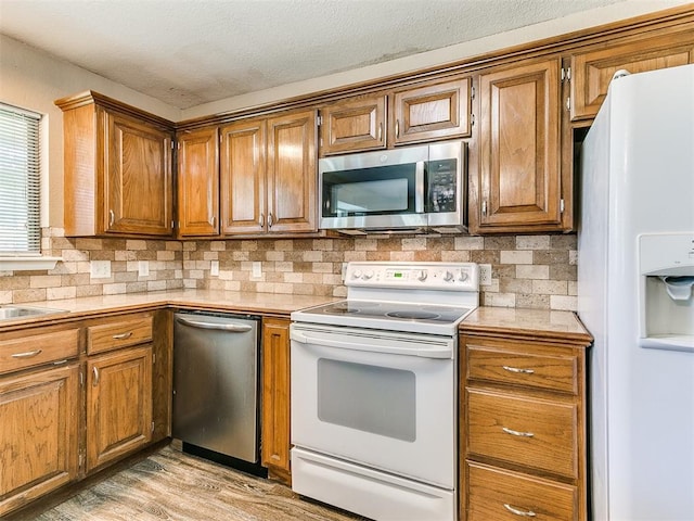 kitchen with backsplash, stainless steel appliances, and light hardwood / wood-style flooring