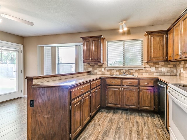 kitchen featuring hardwood / wood-style flooring, kitchen peninsula, sink, and electric stove