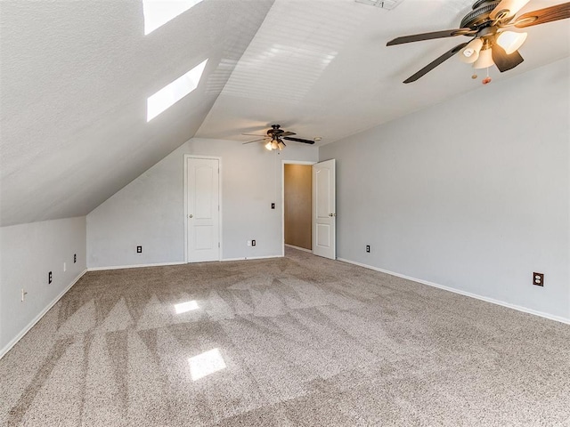 additional living space with a textured ceiling, carpet floors, lofted ceiling with skylight, and ceiling fan