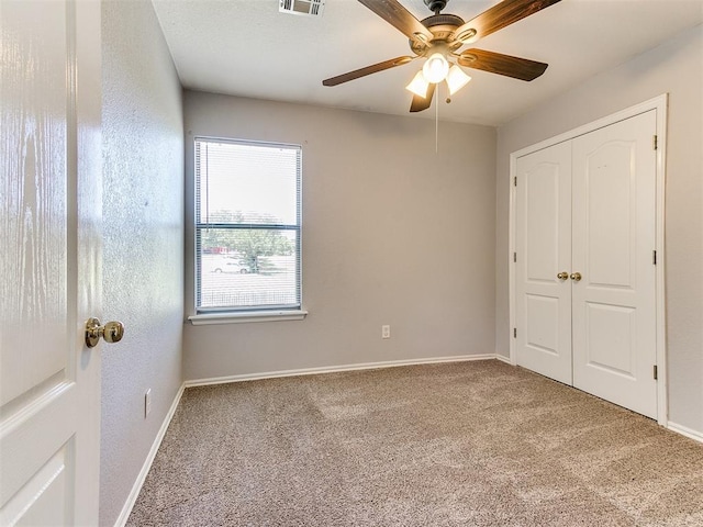 unfurnished bedroom with ceiling fan, a closet, and carpet