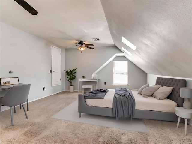 carpeted bedroom with vaulted ceiling with skylight and ceiling fan