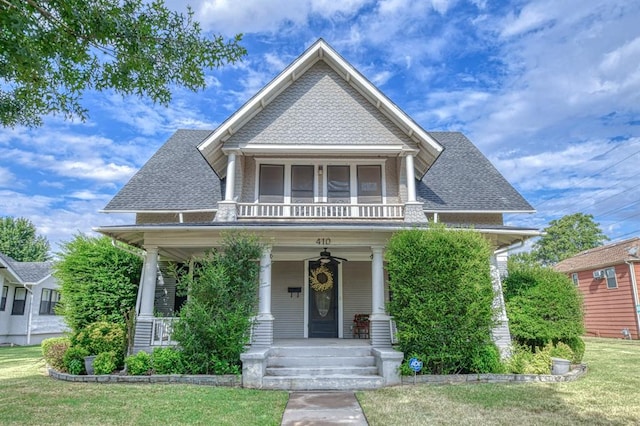 view of front of property featuring covered porch, a balcony, and a front lawn