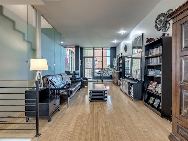 living room featuring light wood-type flooring and a wall of windows