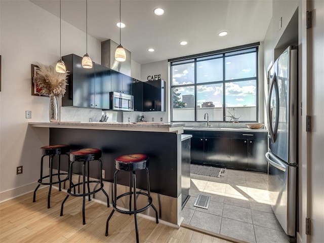 kitchen with pendant lighting, light hardwood / wood-style floors, kitchen peninsula, and stainless steel appliances