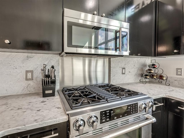 kitchen with light stone countertops, backsplash, and appliances with stainless steel finishes