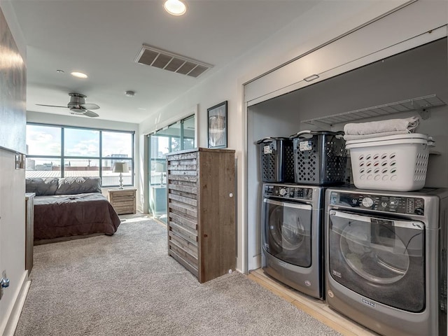 clothes washing area featuring light carpet, independent washer and dryer, and ceiling fan