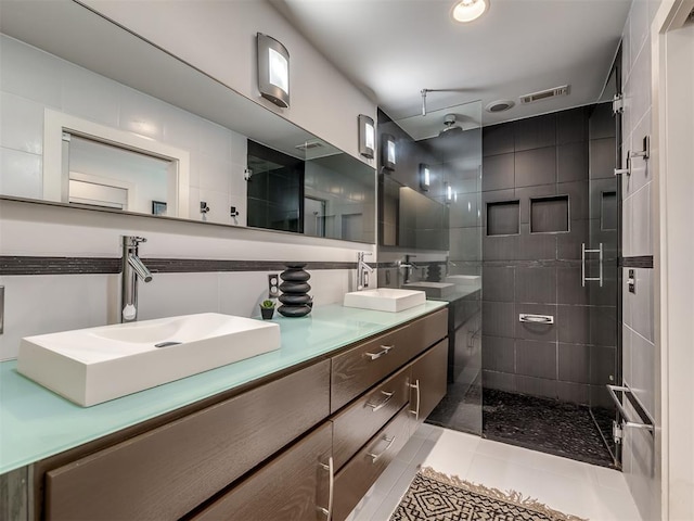 bathroom featuring tile patterned floors, vanity, a shower with shower door, and tile walls