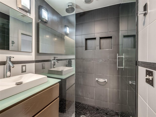 bathroom featuring vanity, tiled shower, and tile walls