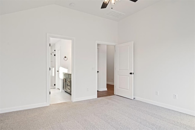 unfurnished bedroom featuring ceiling fan, ensuite bathroom, light carpet, and lofted ceiling