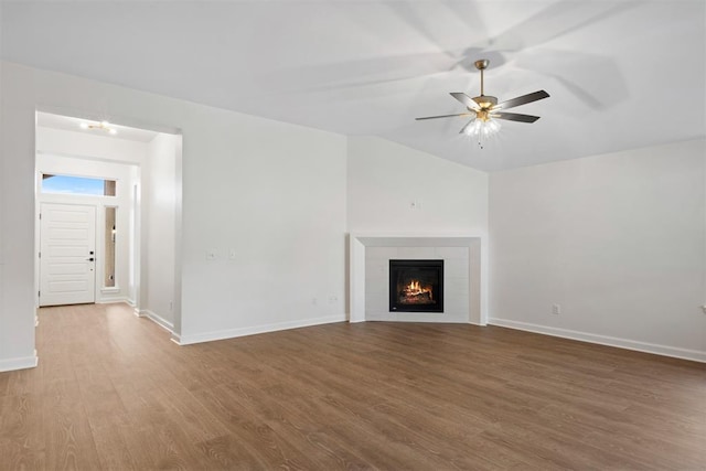 unfurnished living room featuring hardwood / wood-style flooring, ceiling fan, lofted ceiling, and a fireplace