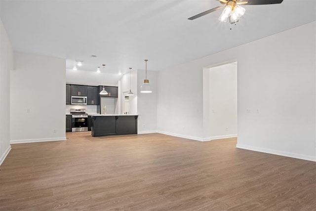 unfurnished living room featuring ceiling fan and hardwood / wood-style floors