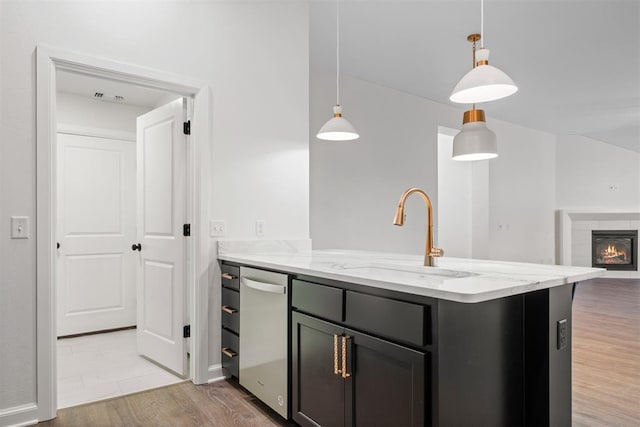 kitchen with sink, light stone countertops, a fireplace, decorative light fixtures, and wood-type flooring