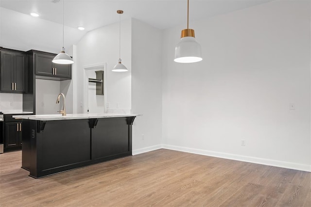 kitchen with a breakfast bar area, light hardwood / wood-style flooring, pendant lighting, and lofted ceiling