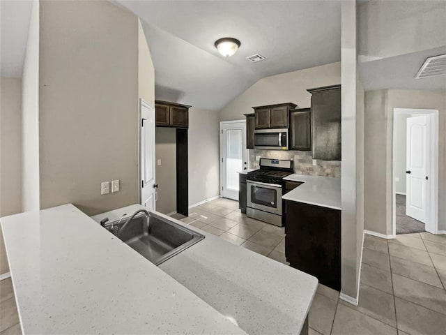 kitchen with tasteful backsplash, stainless steel appliances, vaulted ceiling, sink, and light tile patterned floors