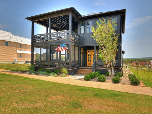 view of front facade featuring a balcony, french doors, and a front lawn