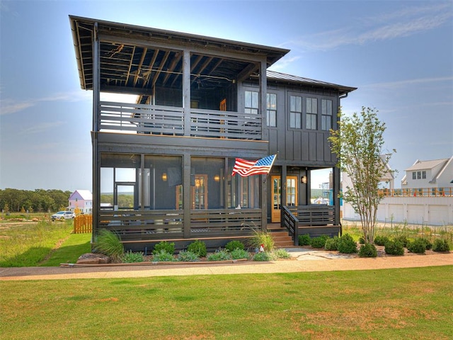 back of house featuring a yard, a balcony, and a sunroom