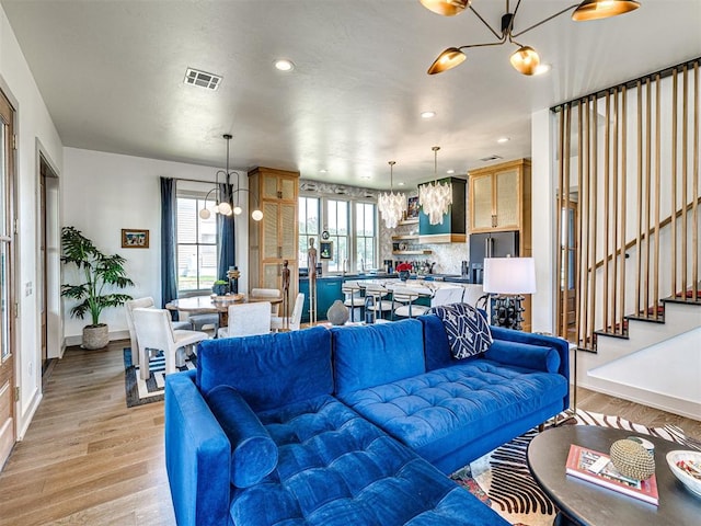 living room with light wood-type flooring and a notable chandelier