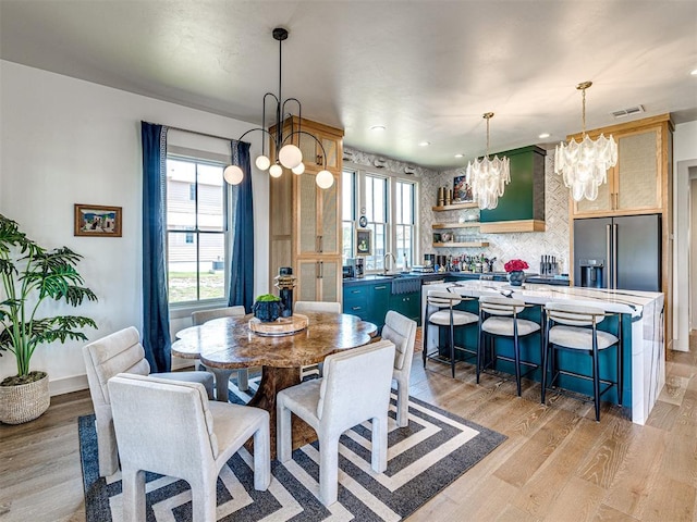 dining room featuring sink, light hardwood / wood-style flooring, and a notable chandelier