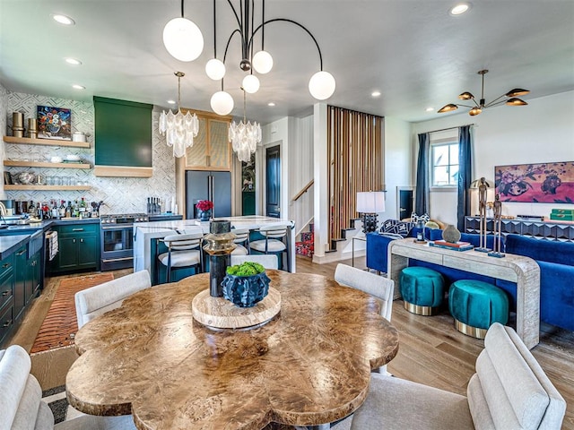 dining area with light hardwood / wood-style flooring and ceiling fan with notable chandelier