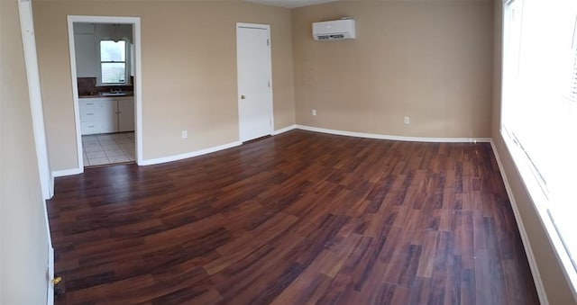 spare room featuring an AC wall unit and dark wood-type flooring