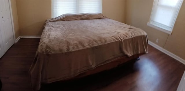 bedroom with dark hardwood / wood-style flooring and a closet