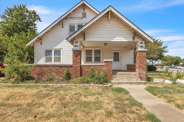 bungalow-style house featuring brick siding, a porch, and a front yard