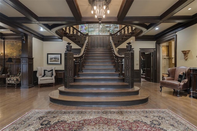 stairs featuring a chandelier, hardwood / wood-style floors, beamed ceiling, and coffered ceiling