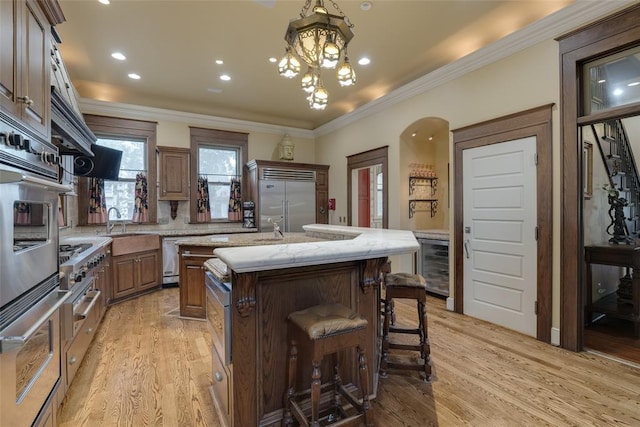 kitchen featuring a center island, wine cooler, ornamental molding, light hardwood / wood-style floors, and stainless steel appliances