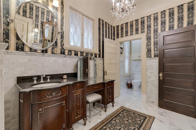 bathroom with vanity, toilet, tile walls, and an inviting chandelier