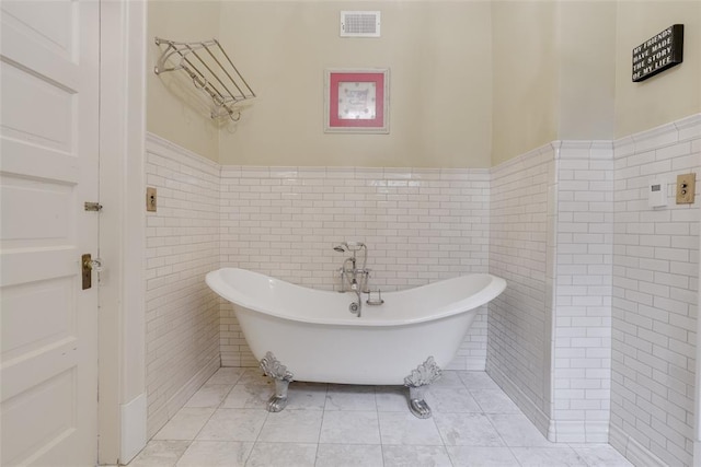 bathroom featuring a washtub, tile walls, and tile patterned flooring