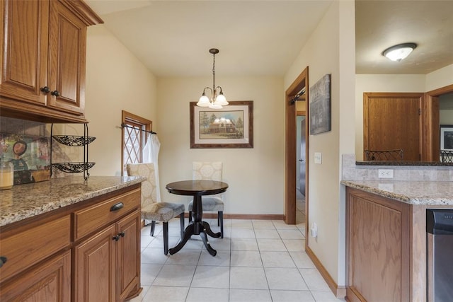 kitchen with decorative backsplash, light stone counters, light tile patterned floors, and a notable chandelier