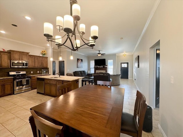 tiled dining area with ceiling fan with notable chandelier, ornamental molding, and sink