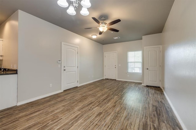 unfurnished living room featuring wood-type flooring and ceiling fan with notable chandelier