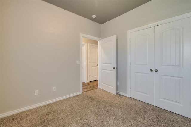 unfurnished bedroom featuring light colored carpet and a closet